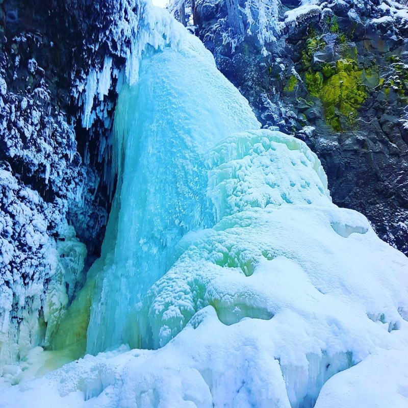 a large waterfall over a snow covered mountain