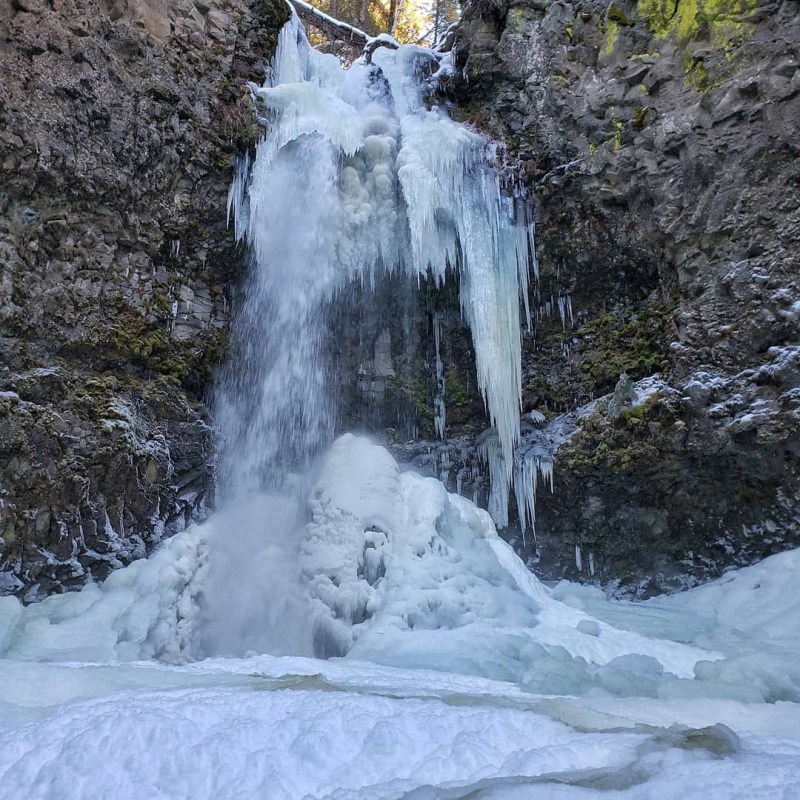 a pile of snow next to a waterfall