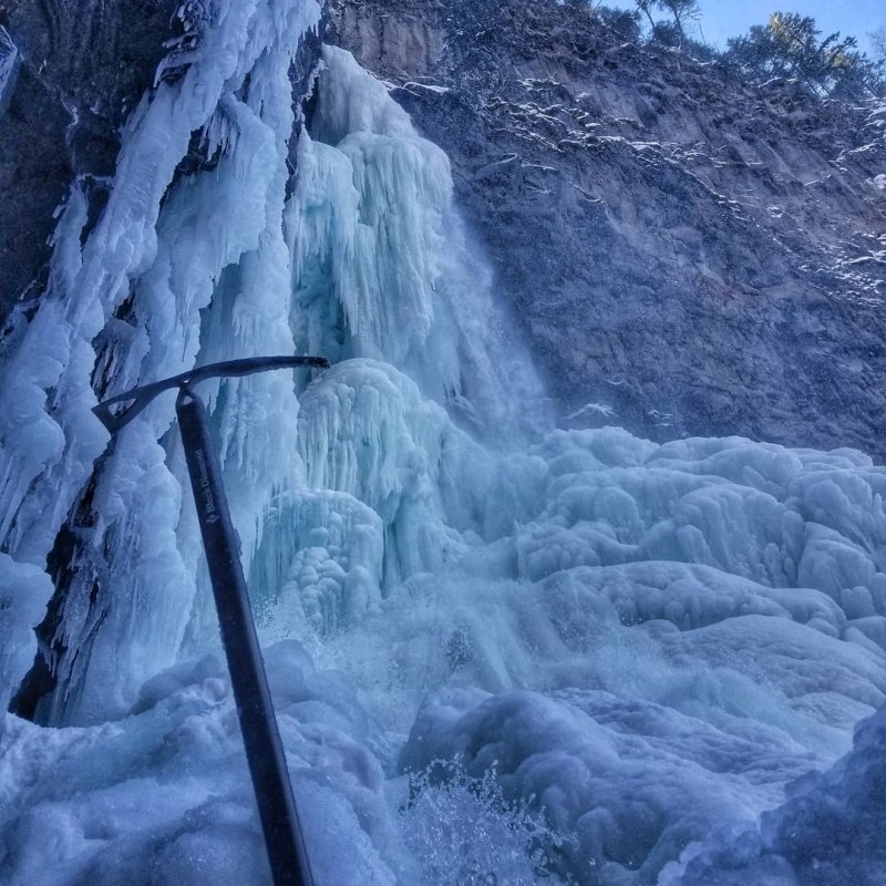 a waterfall with trees on the side of a snow covered slope