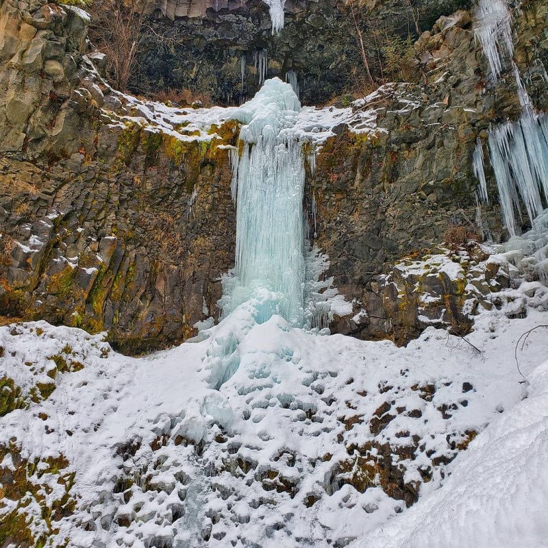 a pile of snow next to a waterfall
