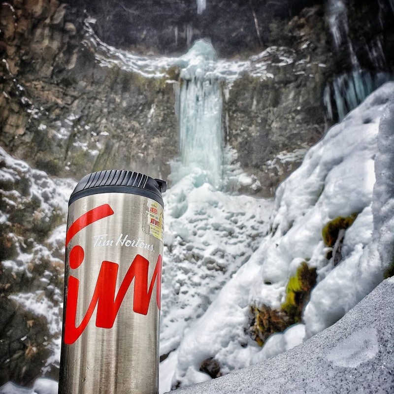 a pile of snow next to a waterfall