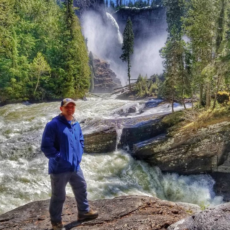 a man standing next to a waterfall