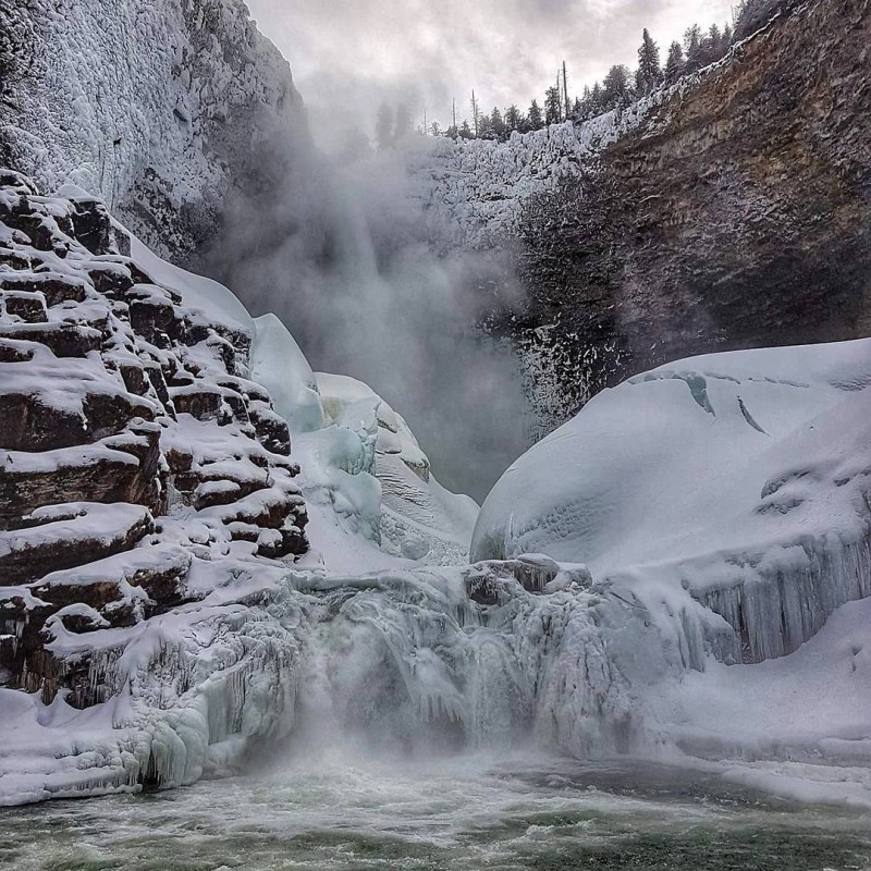 a large waterfall over a snow covered slope