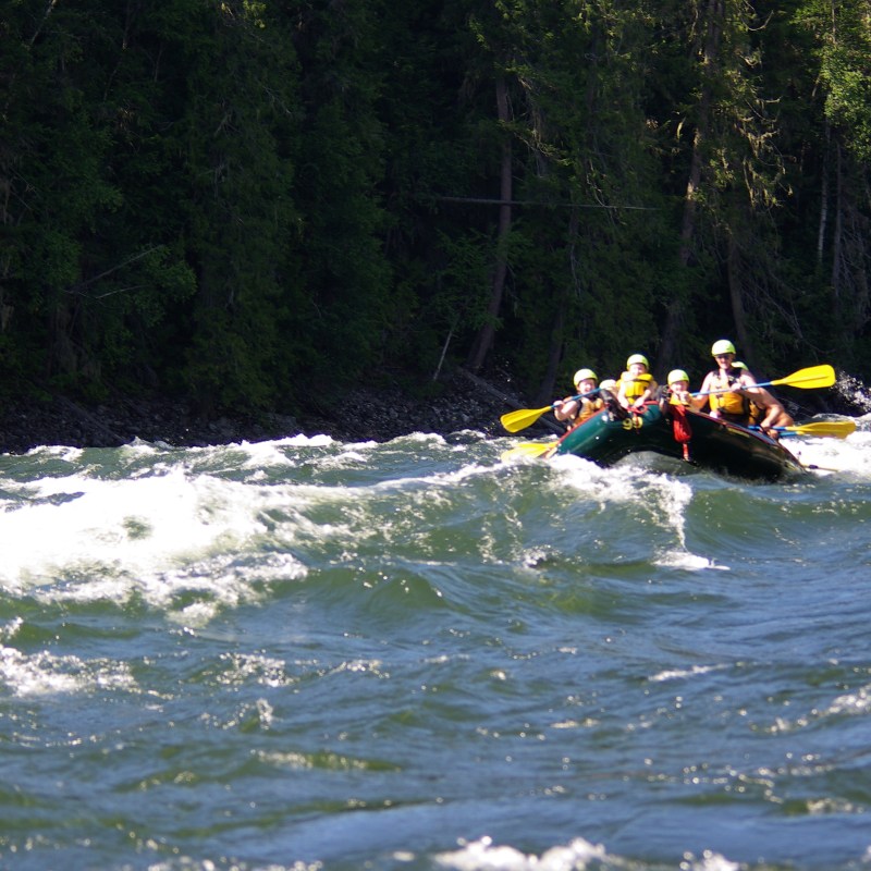 a group of people riding on the back of a boat in the water