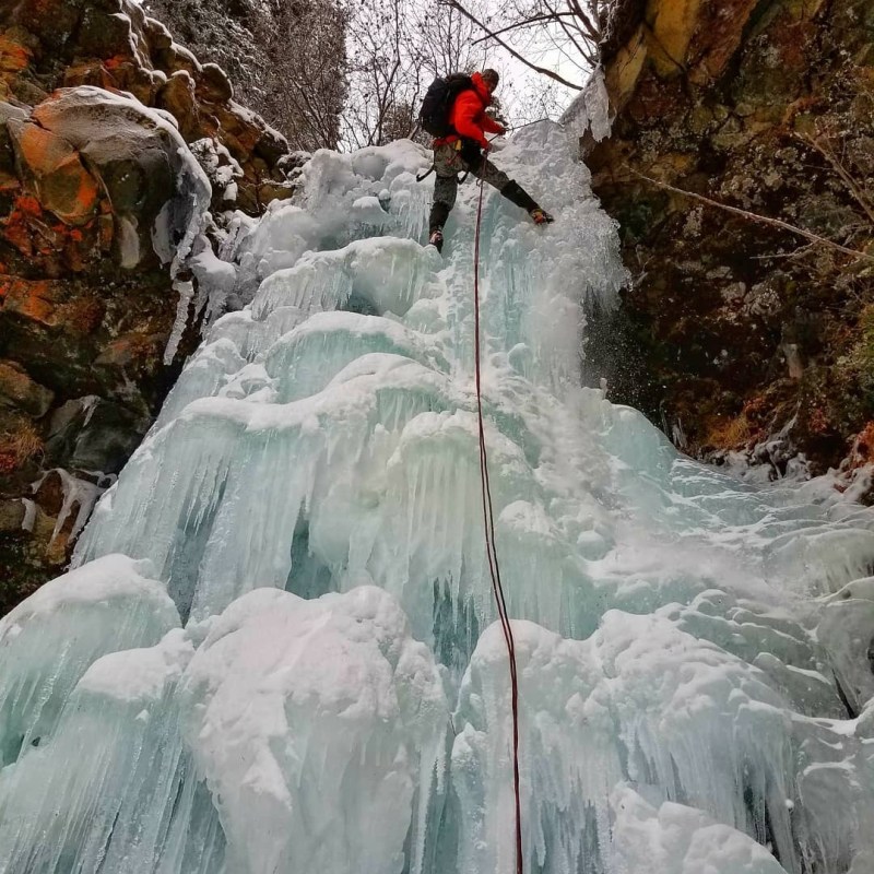 a waterfall with trees on the side of a snow covered slope