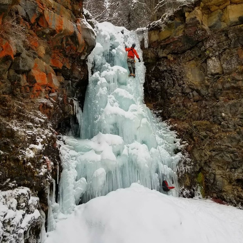 a pile of snow next to a waterfall