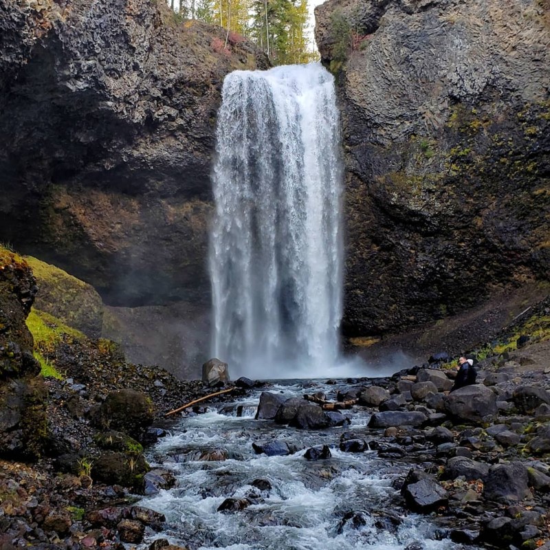 a large waterfall next to a rock