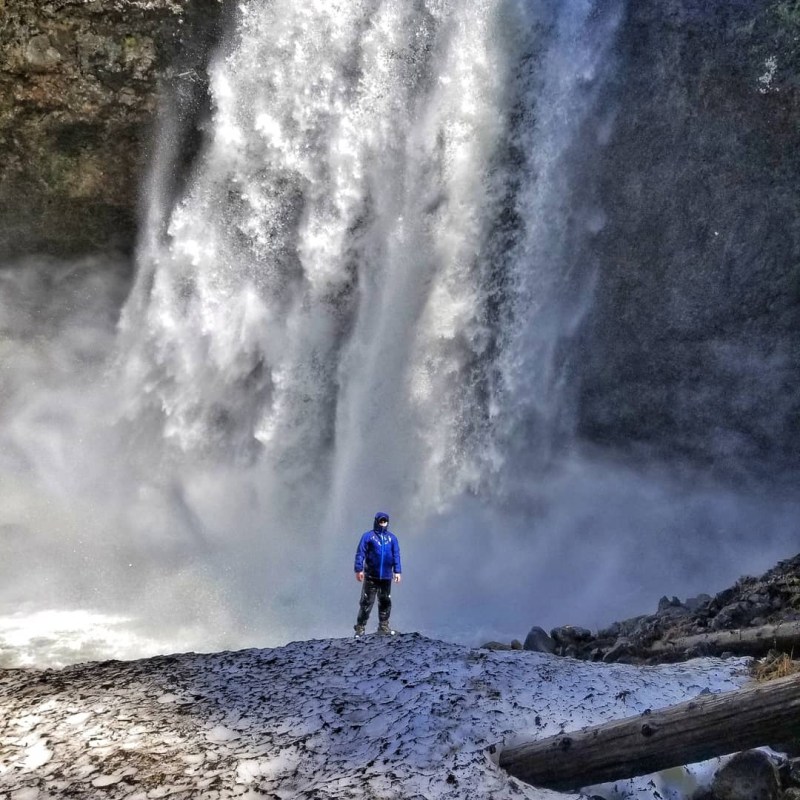a man standing next to a waterfall