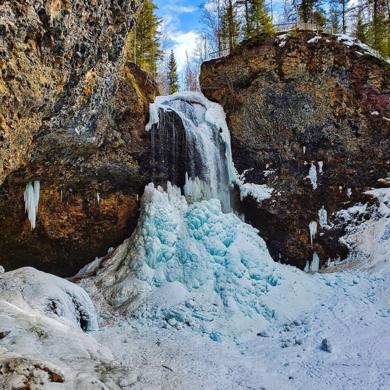 a pile of snow next to a waterfall