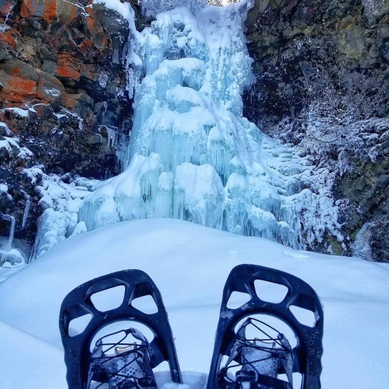 a pile of snow next to a waterfall