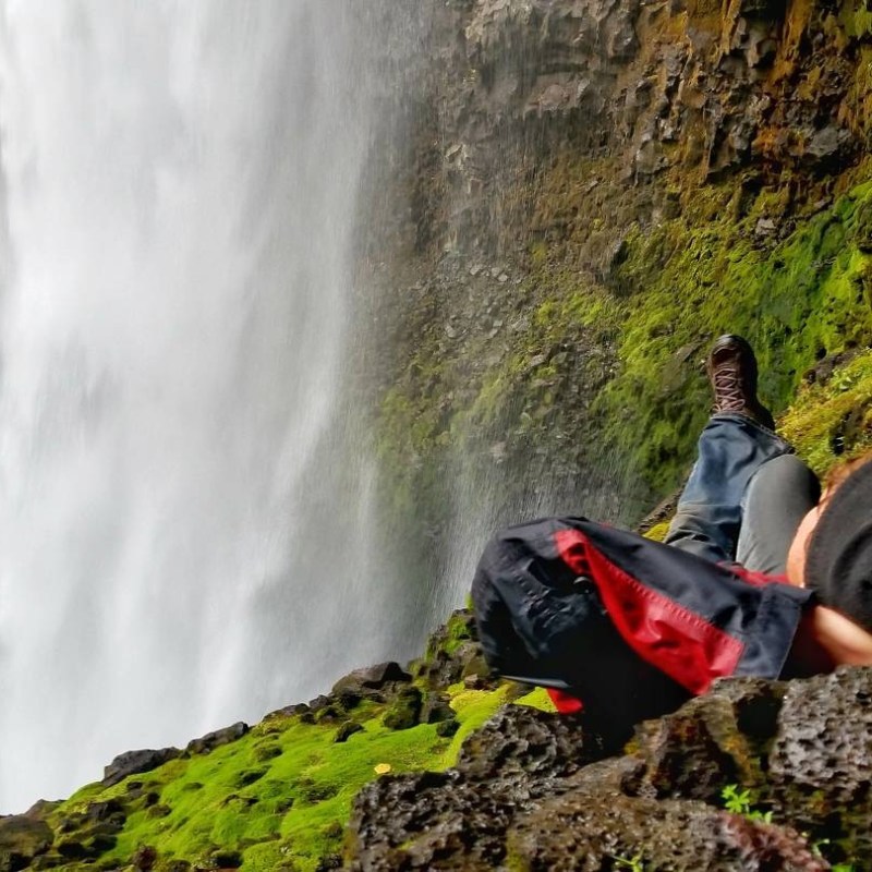 a man standing next to a waterfall