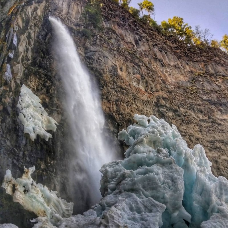 a large waterfall next to a rock