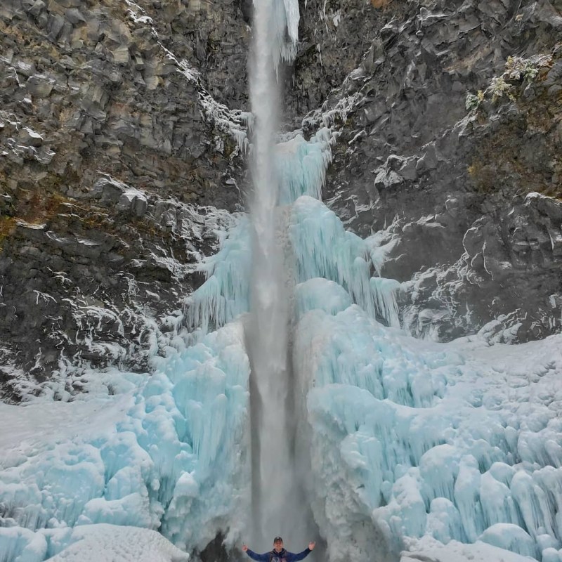 a man standing next to a waterfall