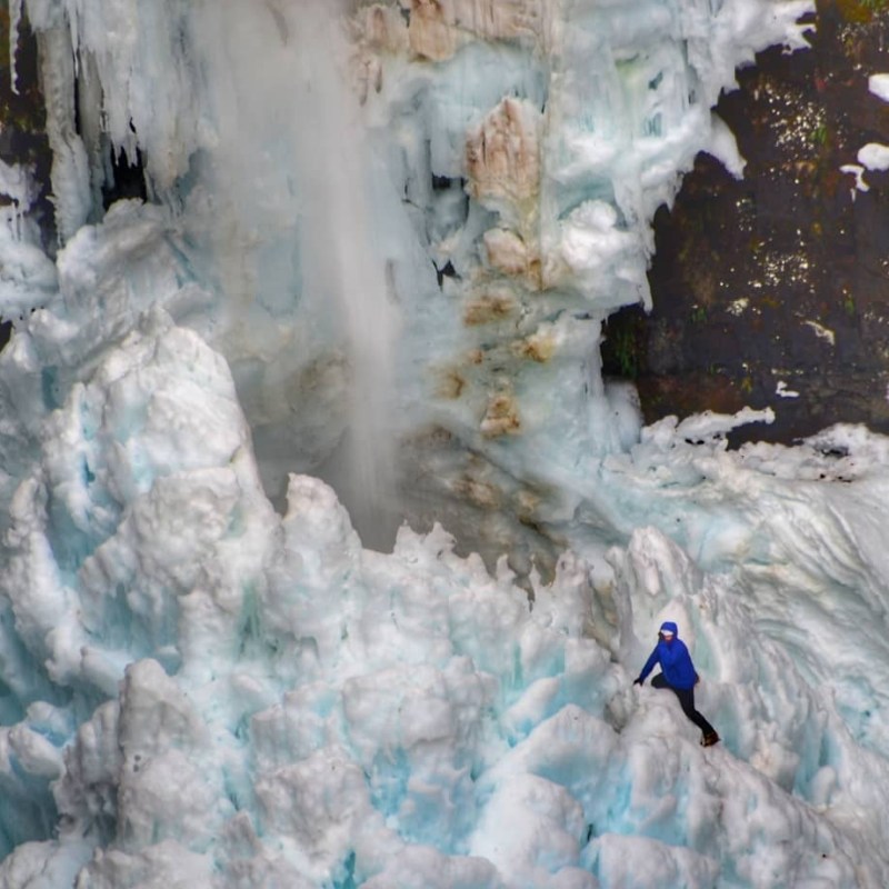 a pile of snow next to a waterfall