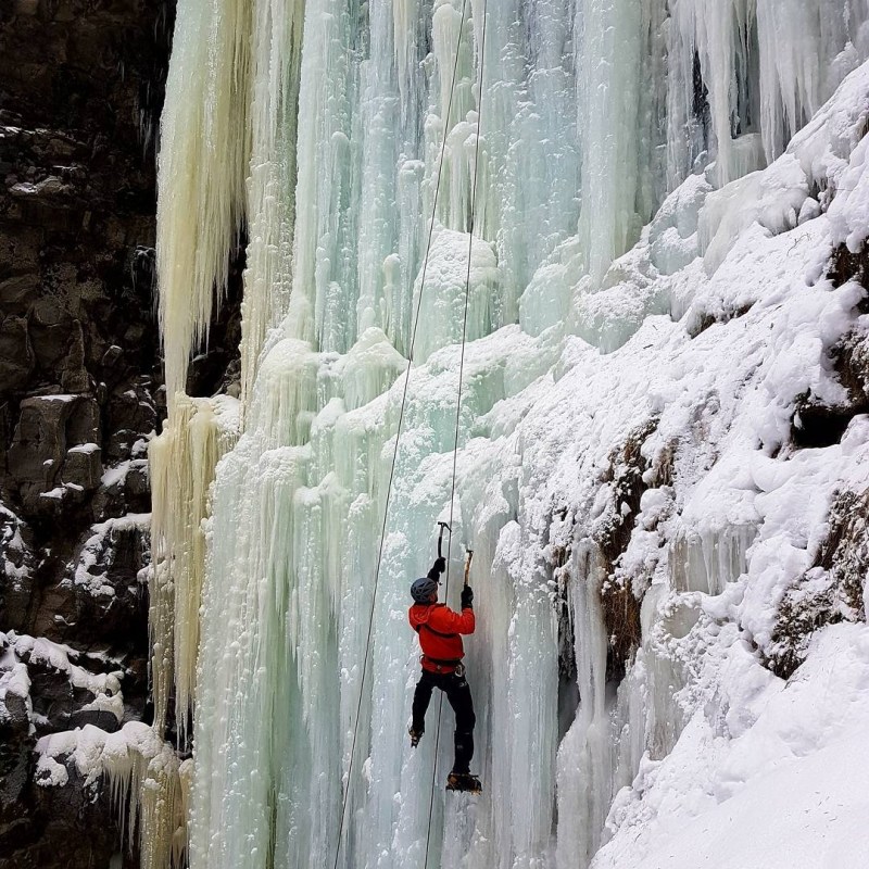 a waterfall with trees on the side of a snow covered slope