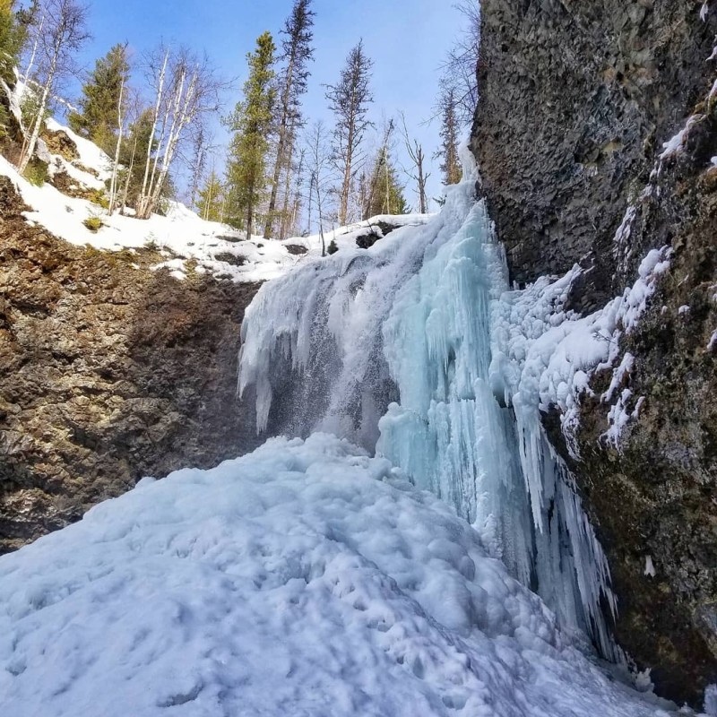 a large waterfall over a snow covered mountain