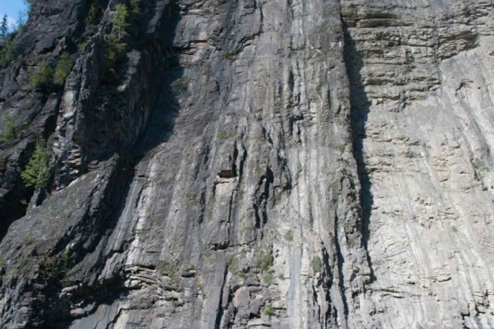 People prepare rafts by a large cliff and river.
