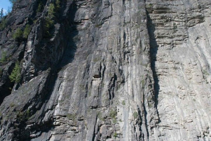 Rafters resting by a river with a tall rock cliff and scattered gear.