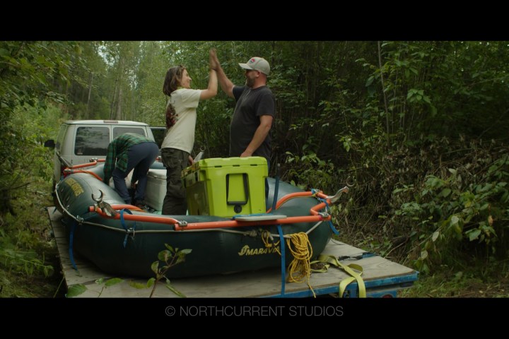 People with an inflatable boat on a trailer in a forest.