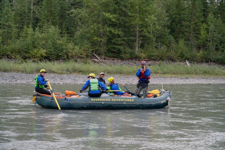 Group of people rafting on a river surrounded by trees.